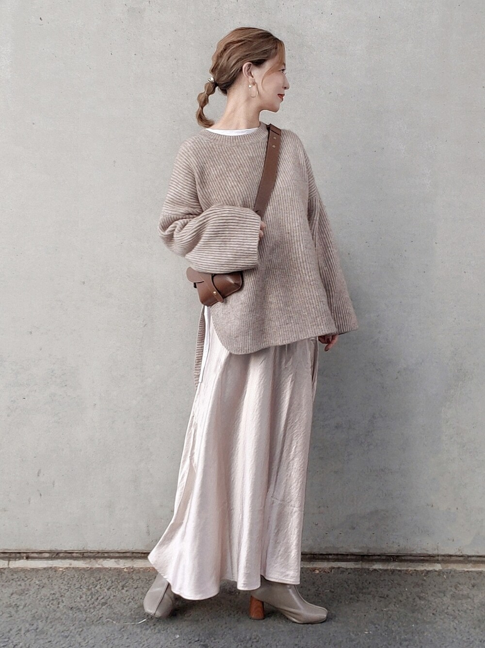 ベージュ系のニット/セーター、ブラウン系のショルダーバッグ、グレー系のブーツを着用したレディースの冬コーディネートの2枚目の写真