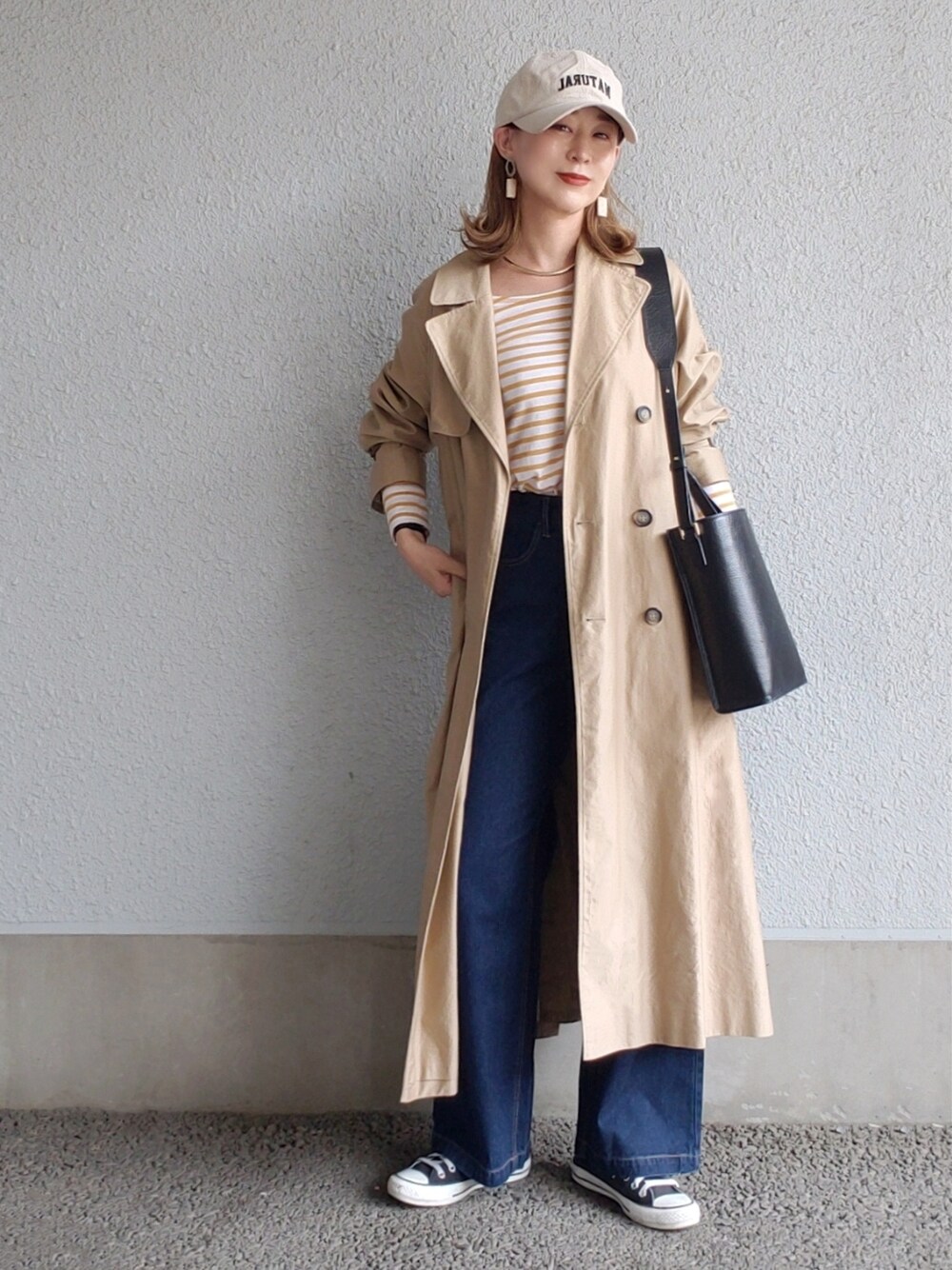 ベージュ系のトレンチコート、ブラック系のバッグ、ブラック系のスニーカーを着用したレディースの春コーディネートの2枚目の写真