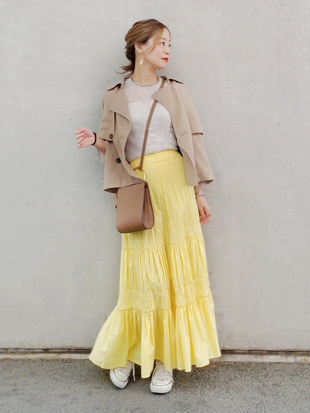 イエロー系のスカート、ベージュ系のニット/セーター、ホワイト系のスニーカーを着用したレディースの春コーディネートの2枚目の写真