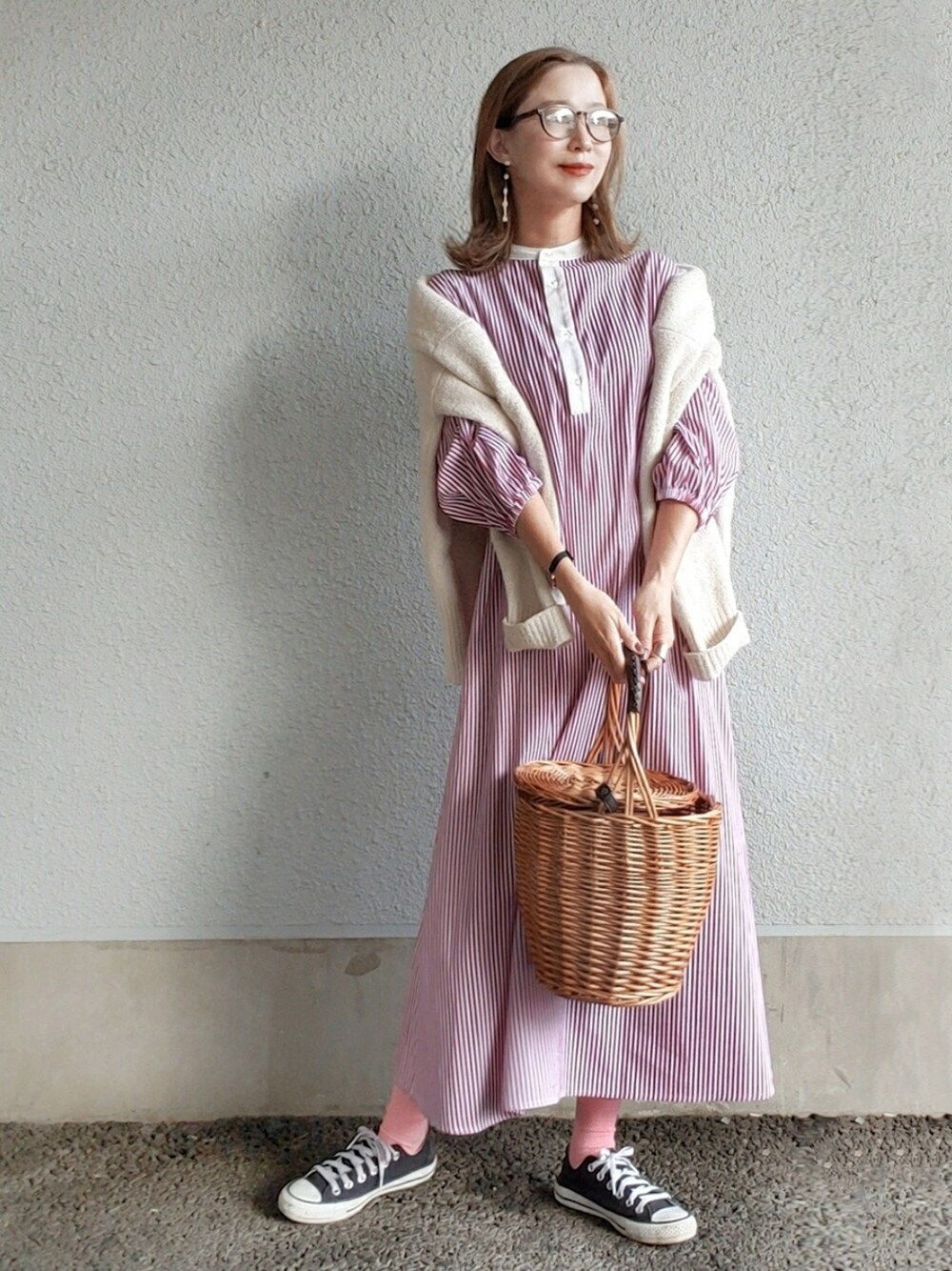 レッド系のシャツワンピース、ベージュ系のかごバッグ、ブラック系のスニーカーを着用したレディースの春コーディネートの2枚目の写真