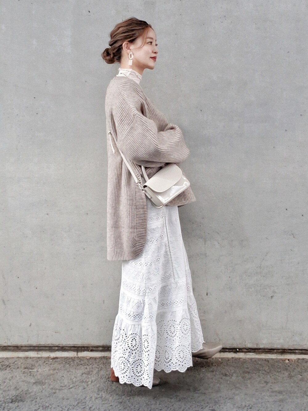 ベージュ系のニット/セーター、ホワイト系のスカート、ベージュ系のTシャツ/カットソーを着用したレディースの冬コーディネートの2枚目の写真