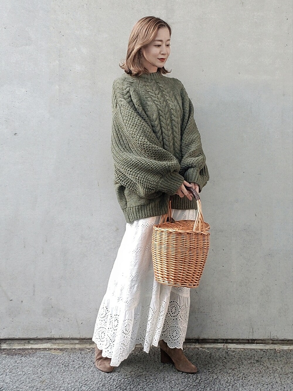 グリーン系のニット/セーター、ホワイト系のスカート、ベージュ系のかごバッグを着用したレディースの冬コーディネートの3枚目の写真