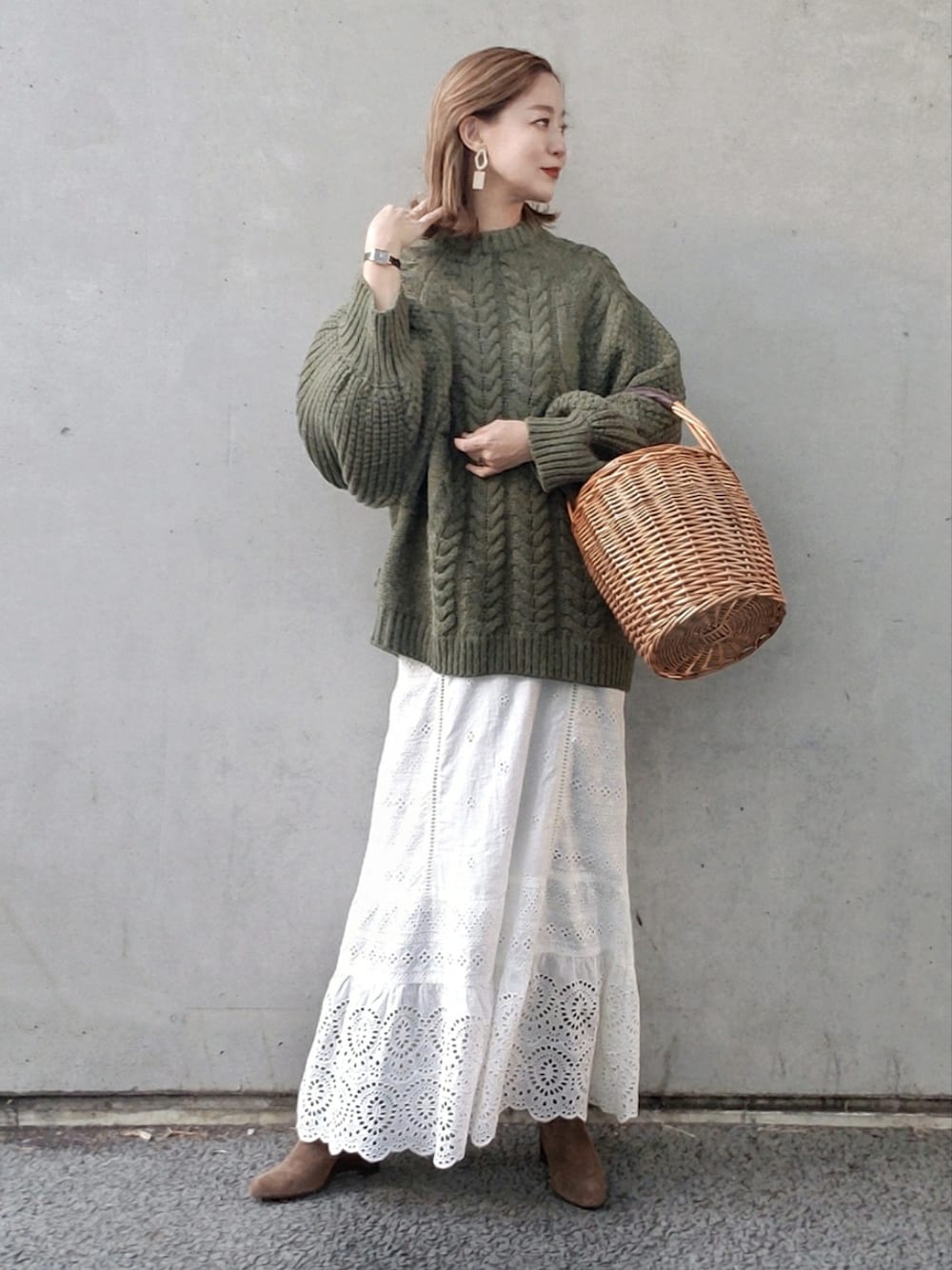 グリーン系のニット/セーター、ホワイト系のスカート、ベージュ系のかごバッグを着用したレディースの冬コーディネートの4枚目の写真