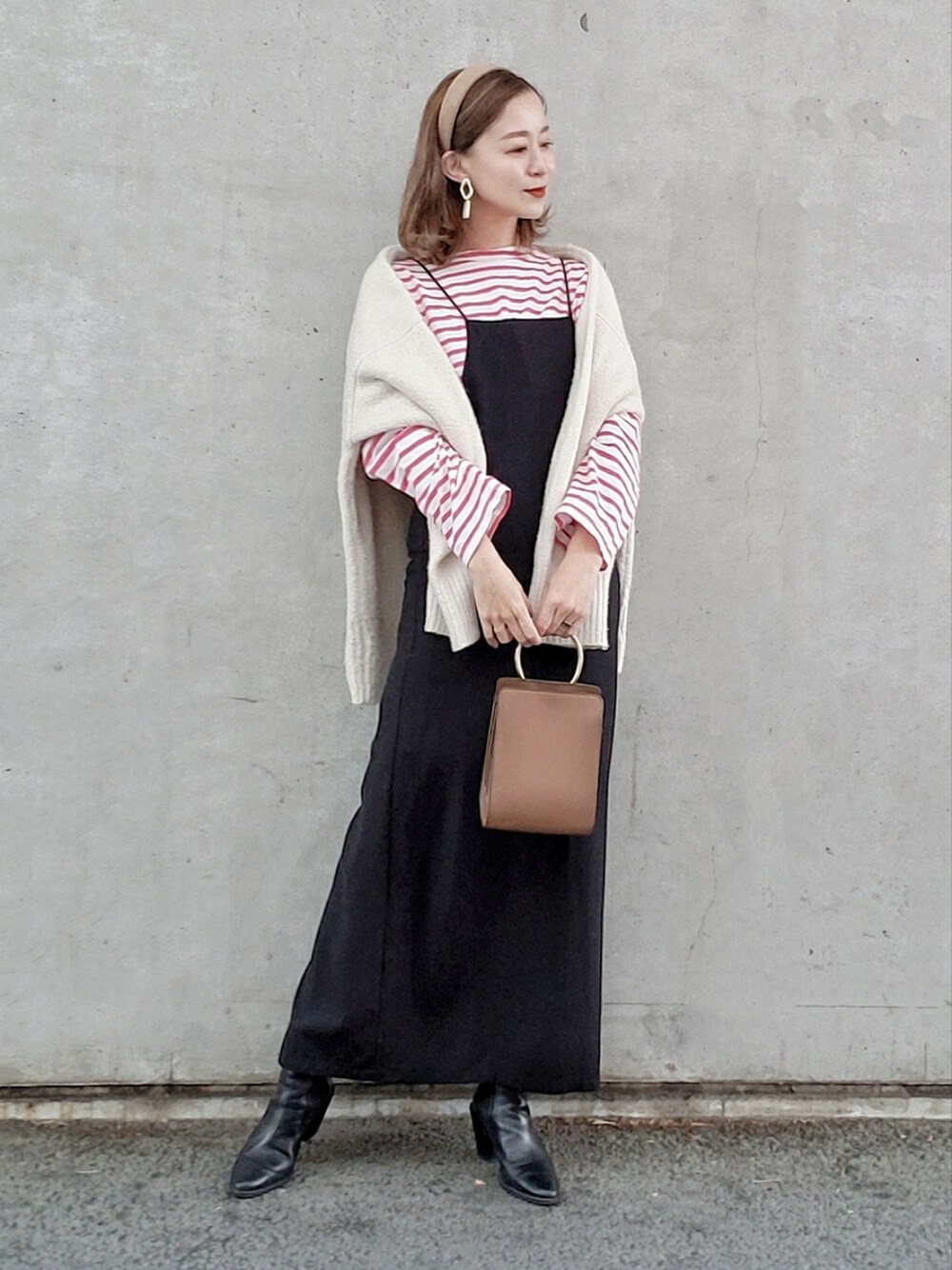 ピンク系のTシャツ/カットソー、ブラック系のワンピース、ブラック系のブーツを着用したレディースの冬コーディネートの2枚目の写真