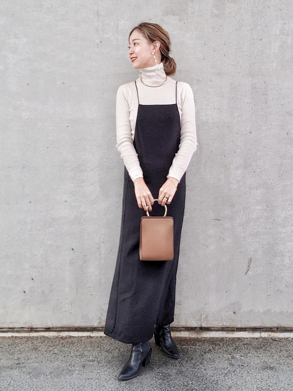 ブラック系のワンピース、ホワイト系のニット/セーター、ブラック系のブーツを着用したレディースの冬コーディネートの2枚目の写真