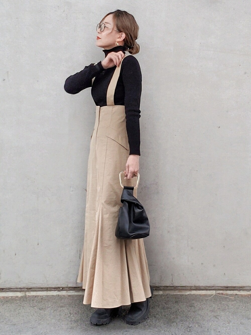 ベージュ系のスカート、ブラック系のニット/セーター、ブラック系のブーツを着用したレディースの冬コーディネートの3枚目の写真