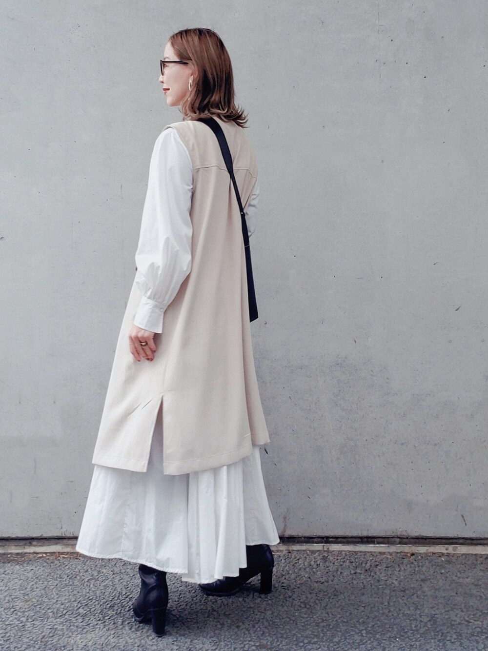 ブラック系のバッグ、ホワイト系のシャツワンピース、ブラック系のブーツを着用したレディースの春コーディネートの3枚目の写真