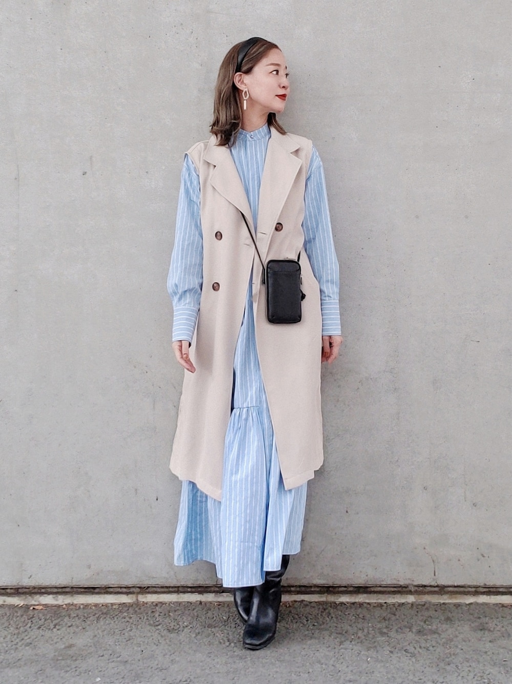 ブルー系のシャツワンピース、ブラック系のブーツ、ブラック系の財布を着用したレディースの春コーディネートの2枚目の写真