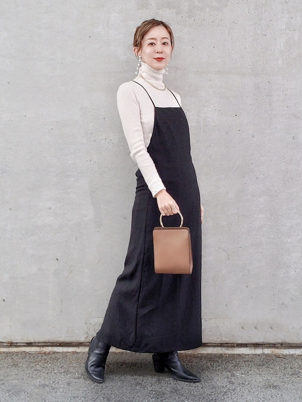 ブラック系のワンピース、ホワイト系のニット/セーター、ブラック系のブーツを着用したレディースの冬コーディネートの4枚目の写真