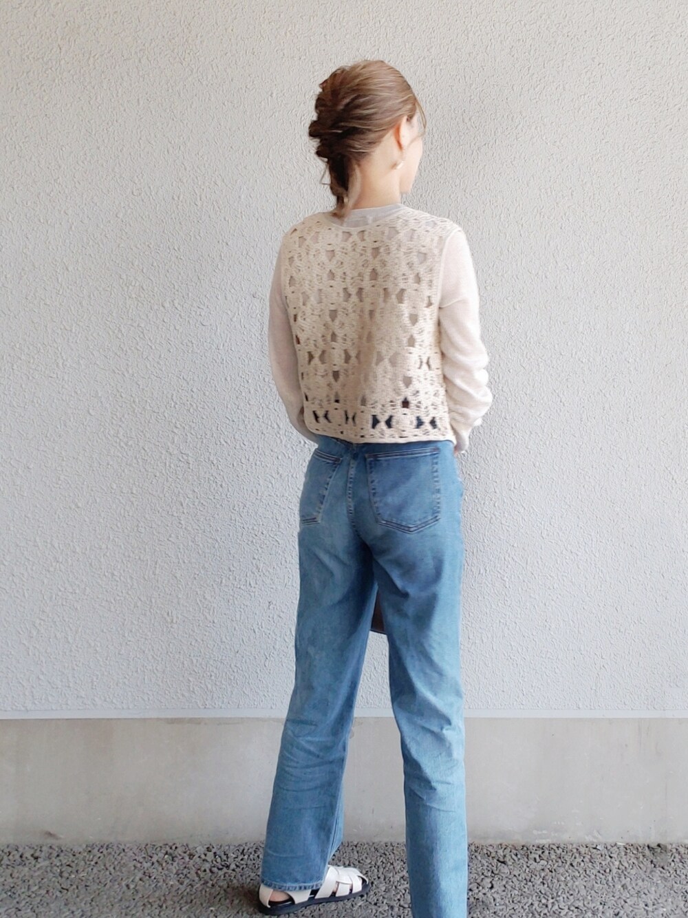 ブラック系のベスト、ベージュ系のニット/セーター、ブルー系のパンツを着用したレディースの春コーディネートの3枚目の写真