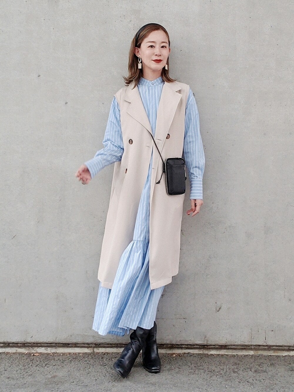 ブルー系のシャツワンピース、ブラック系のブーツ、ブラック系の財布を着用したレディースの春コーディネートの4枚目の写真