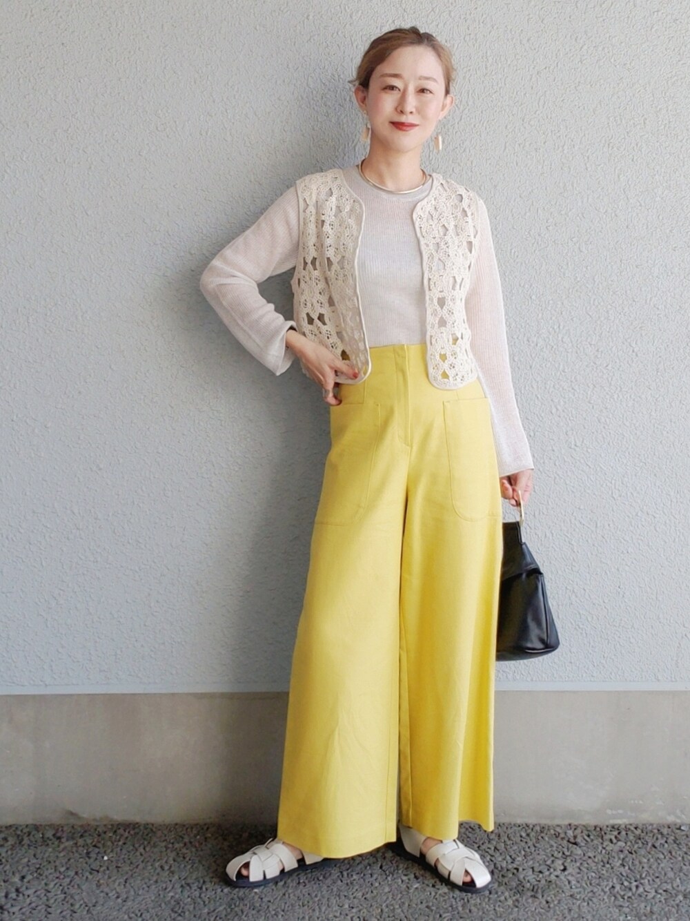 イエロー系のその他パンツ、ブラック系のベスト、ホワイト系のサンダルを着用したレディースの春コーディネートの3枚目の写真
