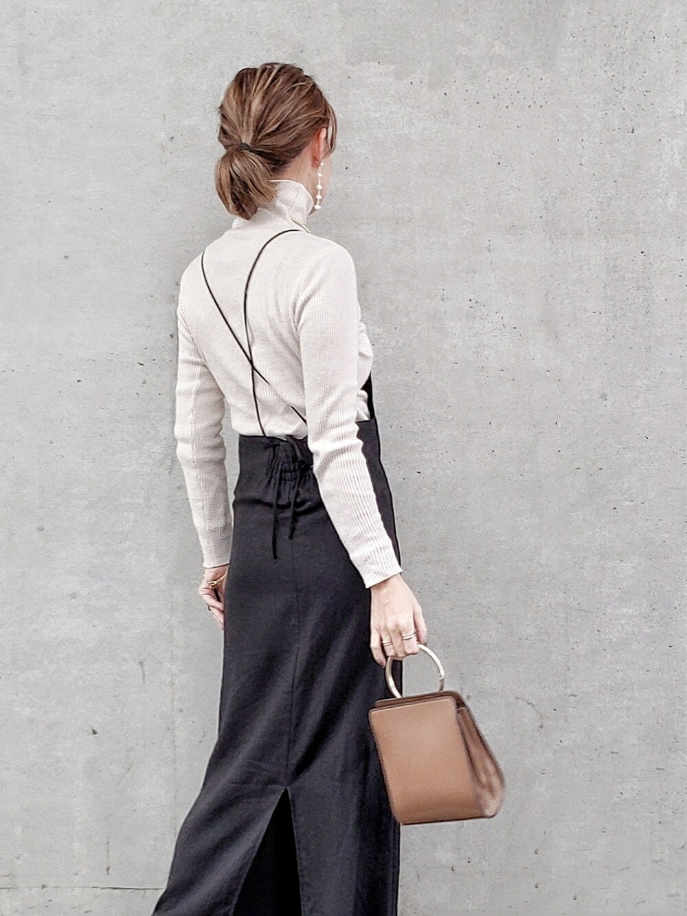 ブラック系のワンピース、ホワイト系のニット/セーター、ブラック系のブーツを着用したレディースの冬コーディネートの3枚目の写真