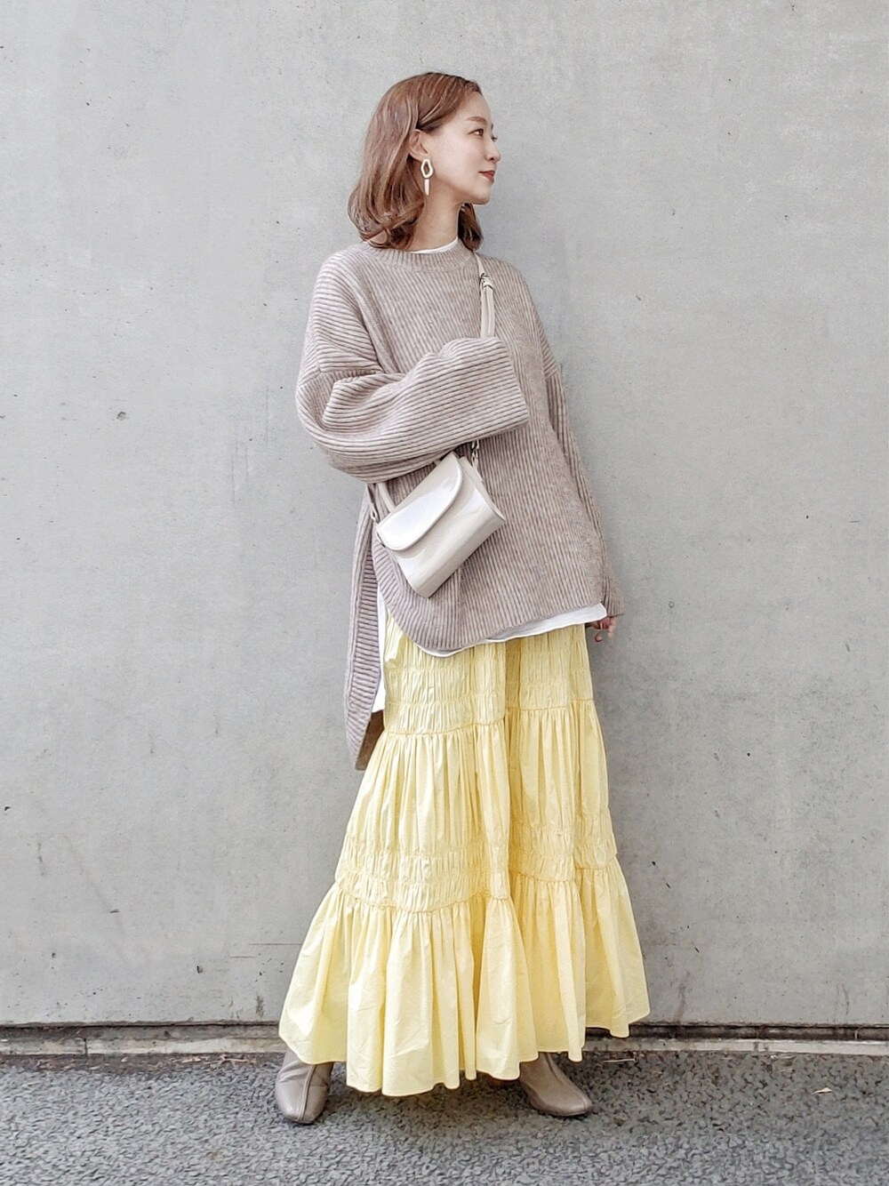 ベージュ系のニット/セーター、イエロー系のスカート、グレー系のブーツを着用したレディースの冬コーディネートの2枚目の写真
