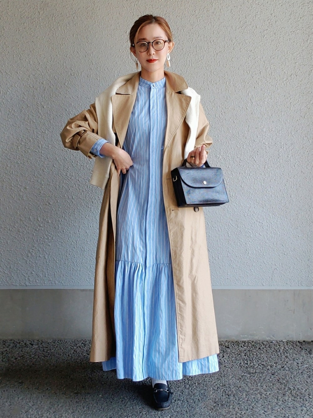 ブルー系のシャツワンピース、ベージュ系のトレンチコート、ブラック系のショルダーバッグを着用したレディースの春コーディネートの3枚目の写真
