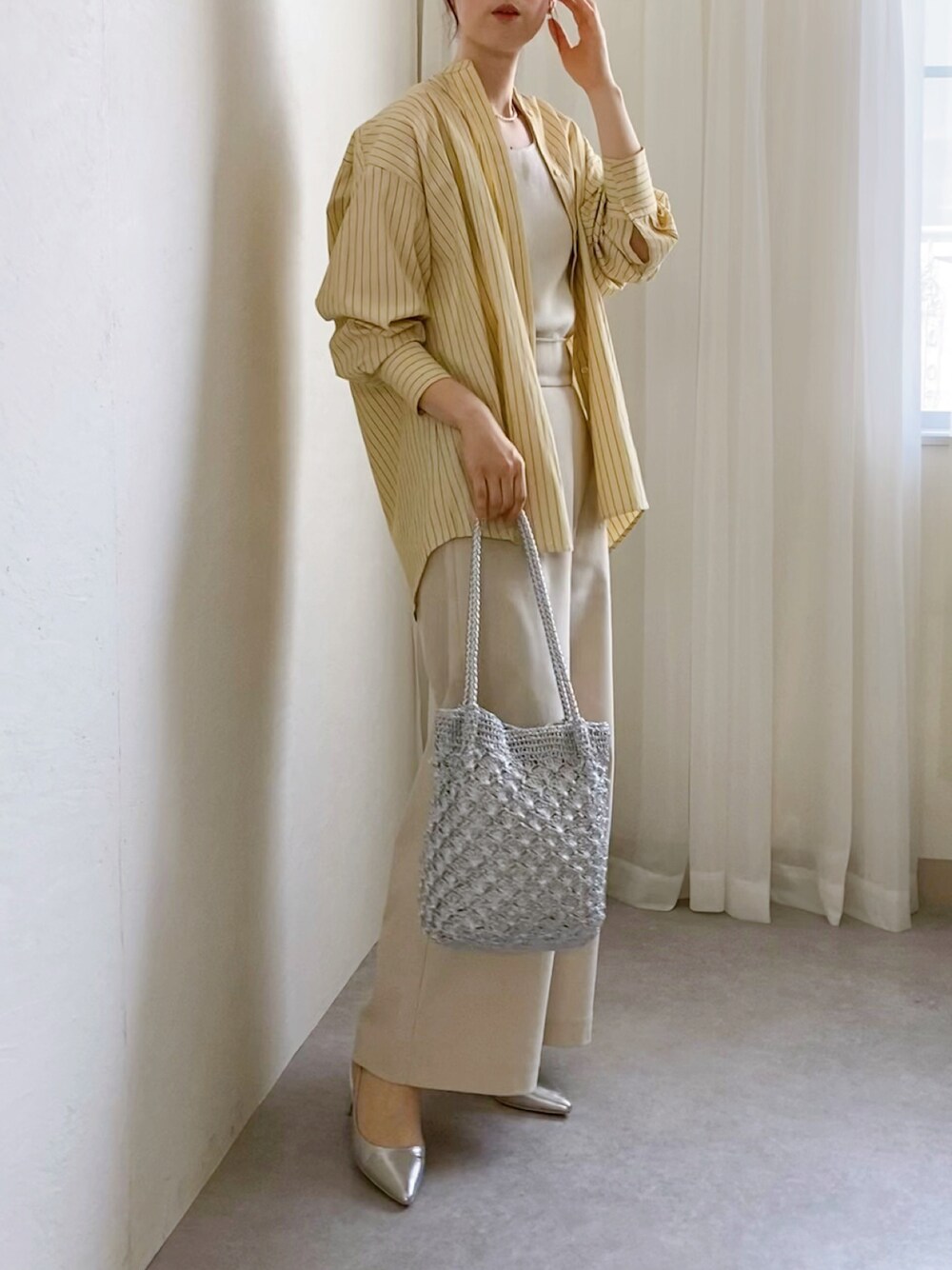 イエロー系のシャツ/ブラウス、ホワイト系のタンクトップ、シルバー系のトートバッグを着用したレディースの春コーディネートの1枚目の写真