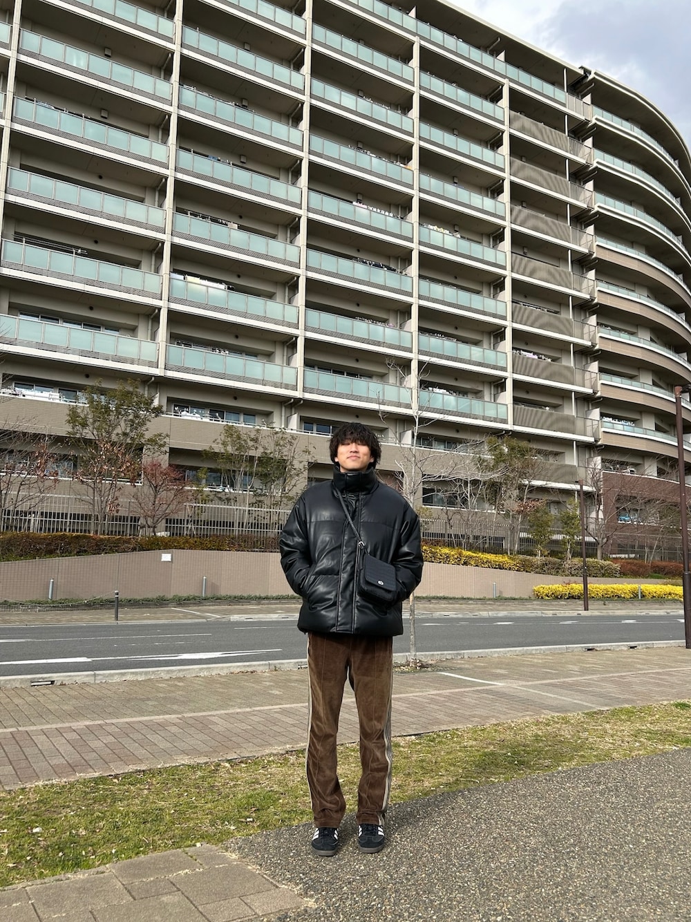 ブラック系のダウンジャケット/コート、ブラック系のショルダーバッグ、ブラック系のスニーカーを着用したメンズの冬コーディネートの1枚目の写真