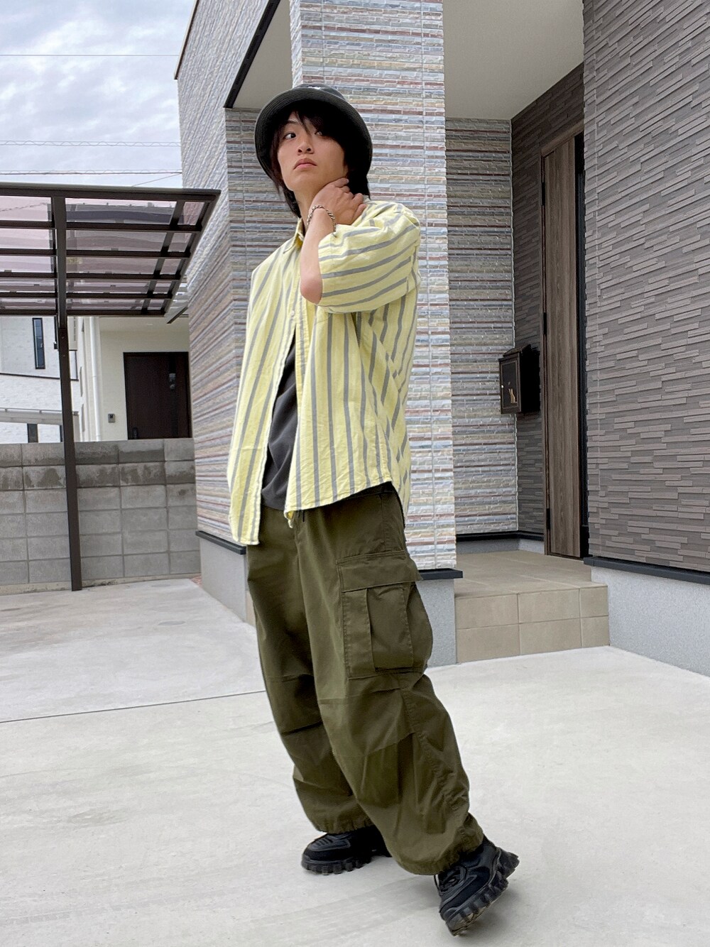 イエロー系のシャツ/ブラウス、ブラック系のTシャツ/カットソー、グリーン系のカーゴパンツを着用したメンズの春コーディネートの1枚目の写真