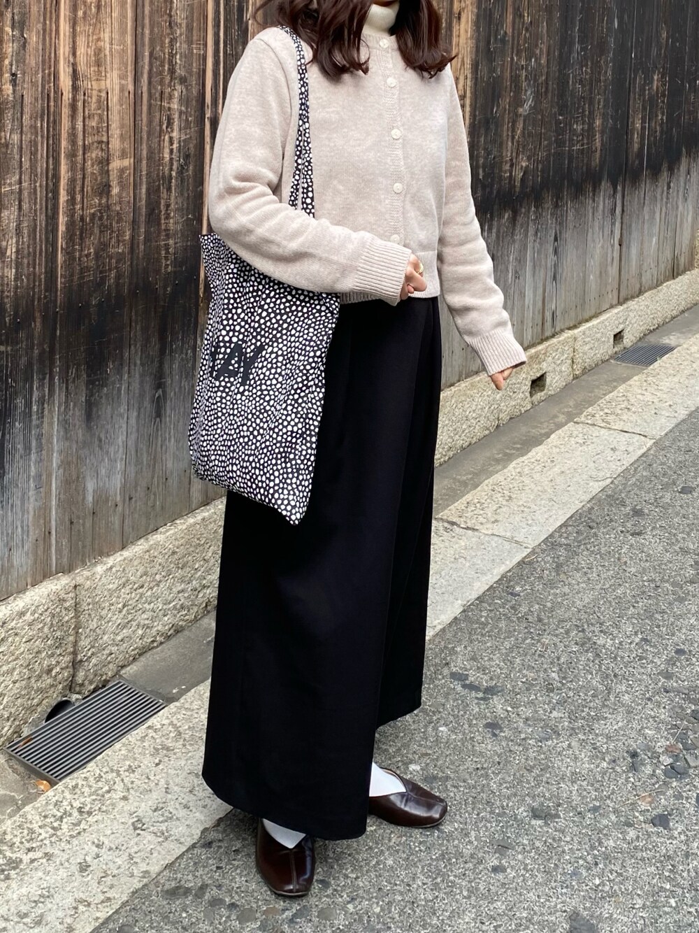 ブラウン系のパンプス、ベージュ系のカーディガン/ボレロ、ブラック系のスカートを着用したレディースの冬コーディネートの1枚目の写真