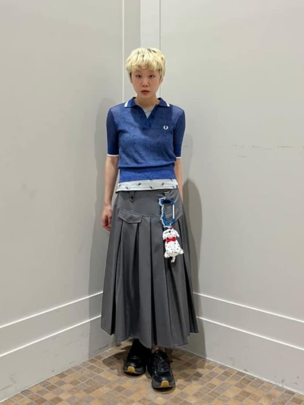 ブルー系のポロシャツ、シルバー系のスカート、グレー系のタンクトップを着用したレディースの夏コーディネートの1枚目の写真