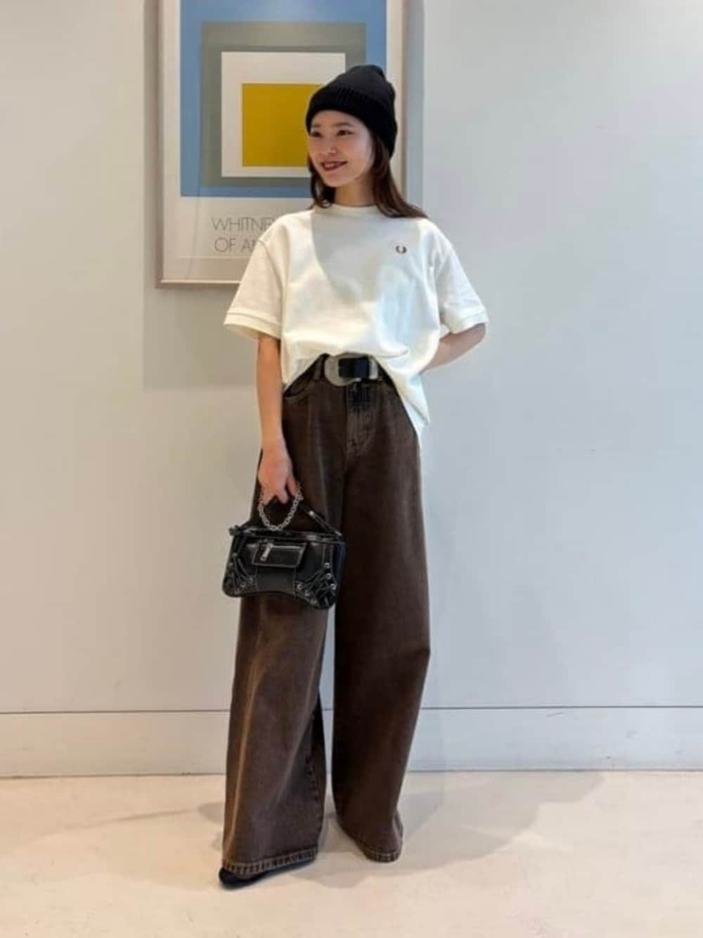 ブラウン系のデニムパンツ、ホワイト系のTシャツ/カットソー、ブラック系のショルダーバッグを着用したレディースの冬コーディネートの1枚目の写真