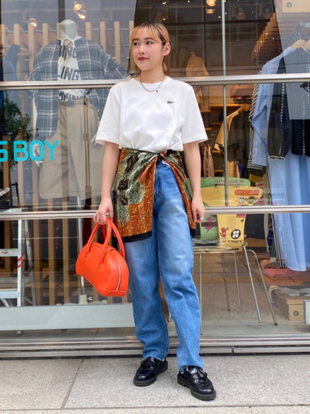 ブルー系のデニムパンツ、ホワイト系のTシャツ/カットソー、オレンジ系のボストンバッグを着用したレディースの夏コーディネートの1枚目の写真