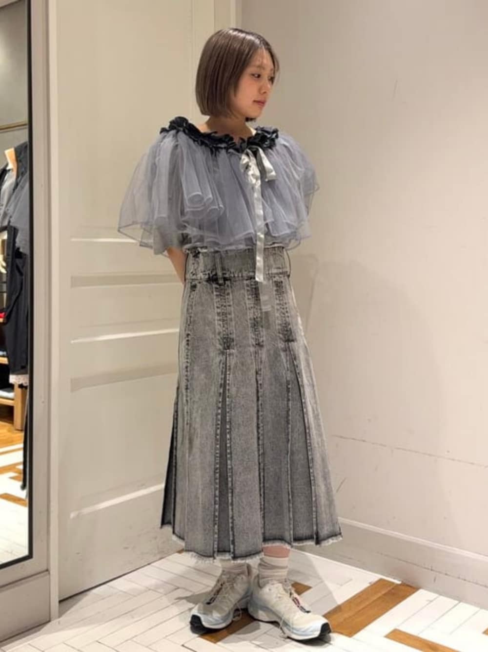 ホワイト系のスニーカー、グレー系のデニムスカートを着用したレディースの春コーディネートの1枚目の写真