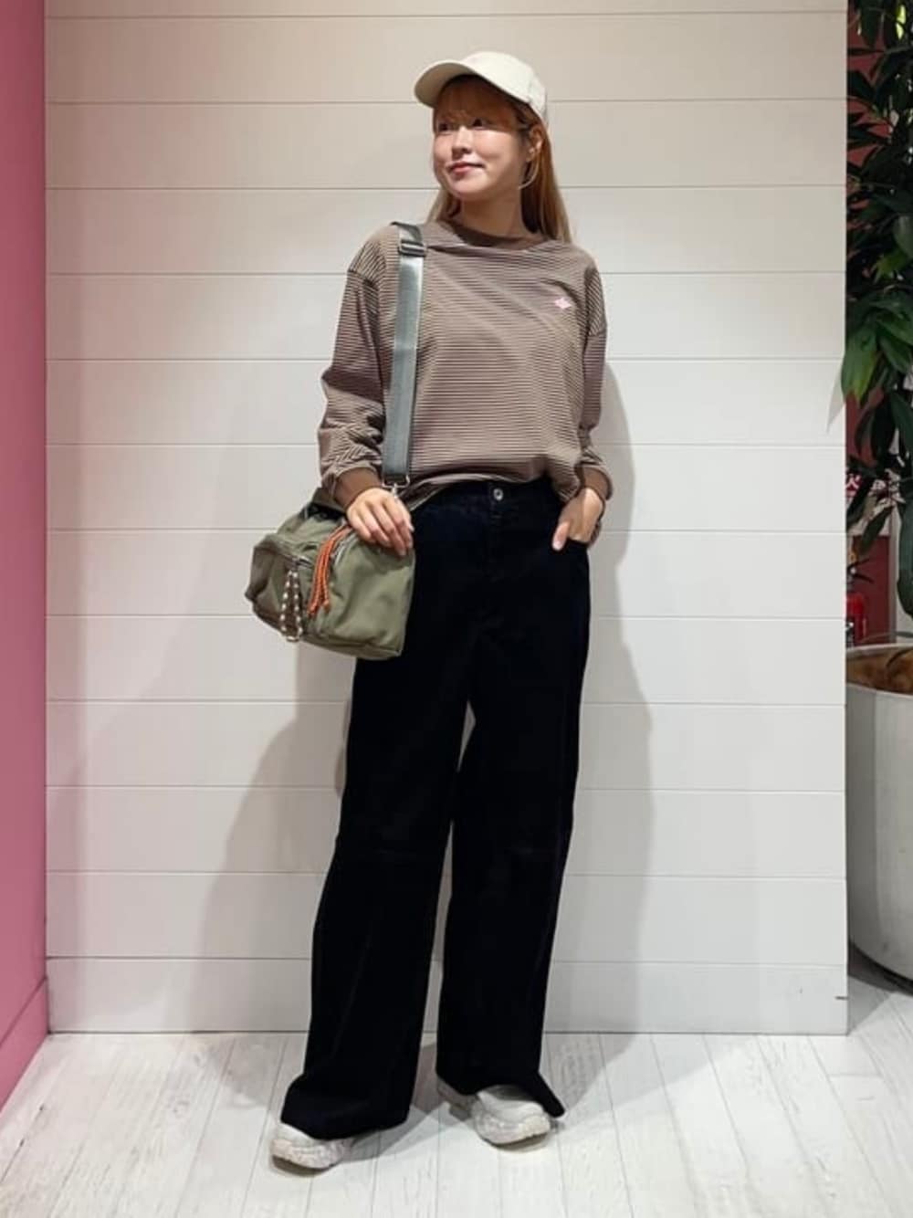 グリーン系のトートバッグ、ブラウン系のTシャツ/カットソー、ブラック系のデニムパンツを着用したレディースの秋コーディネートの1枚目の写真