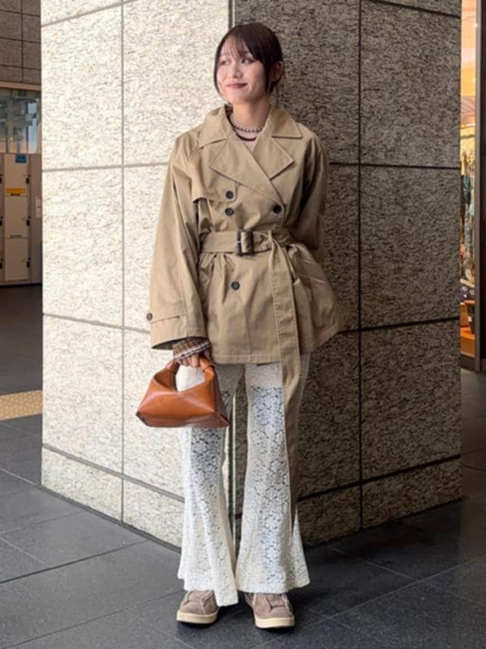 ブラウン系のショルダーバッグ、ブラウン系のトレンチコート、ホワイト系のその他パンツを着用したレディースの春コーディネートの1枚目の写真
