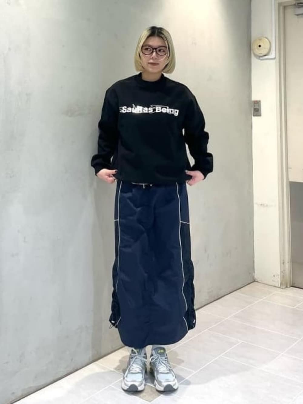 ブルー系のスカート、グレー系のスニーカーを着用したレディースの春コーディネートの1枚目の写真