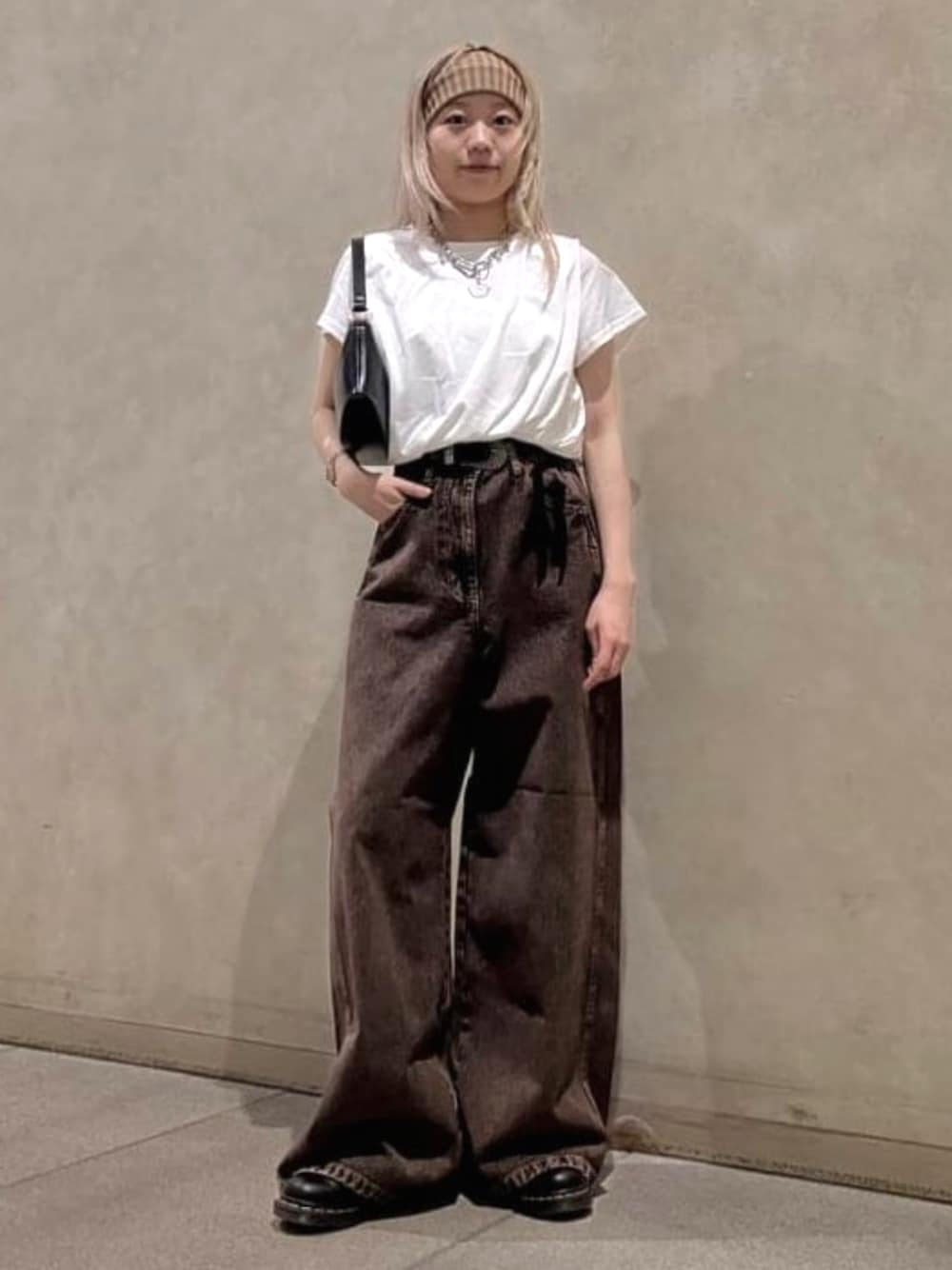 ブラウン系のデニムパンツ、ブラック系のトートバッグ、ホワイト系のTシャツ/カットソーを着用したレディースの夏コーディネートの1枚目の写真