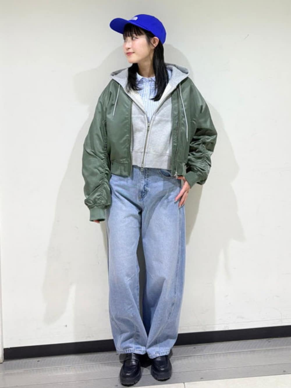 ブルー系のデニムパンツ、グレー系のパーカー、グリーン系のMA-1を着用したレディースの冬コーディネートの1枚目の写真