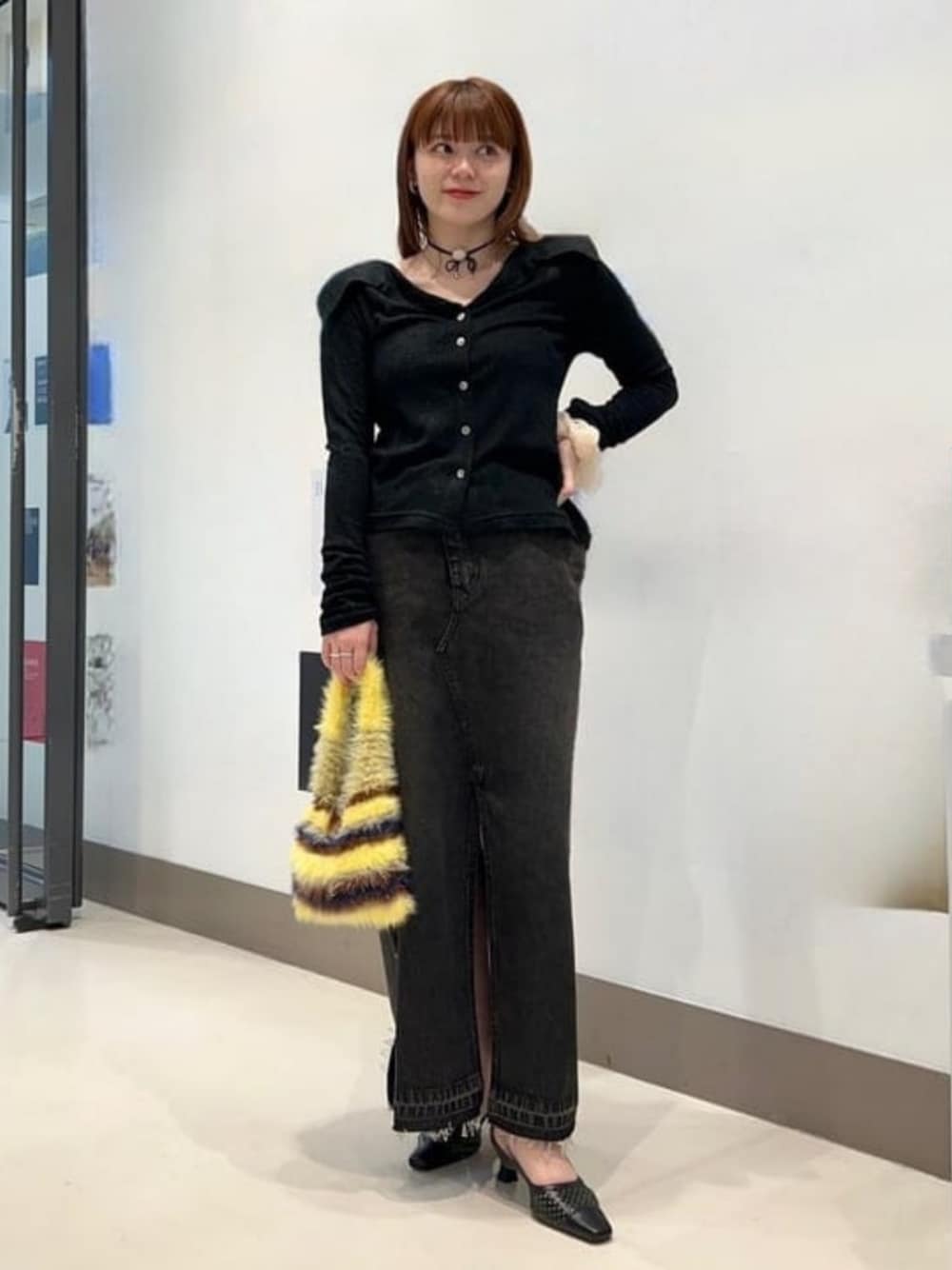 ブラック系のスカート、イエロー系のトートバッグ、ブラック系のシャツ/ブラウスを着用したレディースの秋コーディネートの1枚目の写真