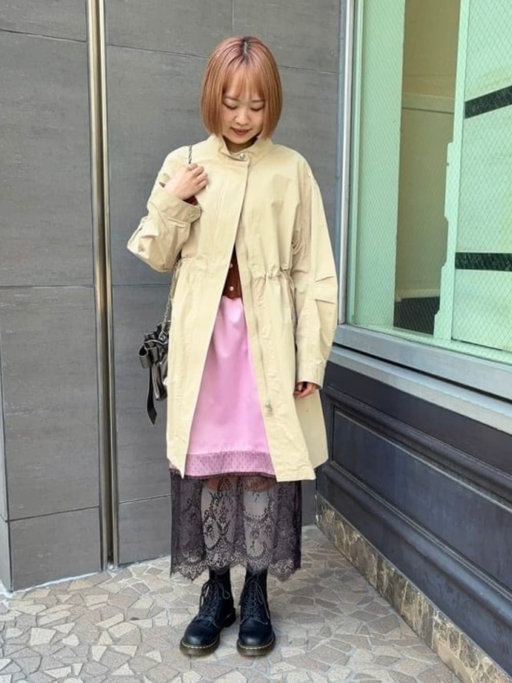 ブラック系のショルダーバッグ、ブラウン系のニット/セーター、ピンク系のスカートを着用したレディースの冬コーディネートの1枚目の写真