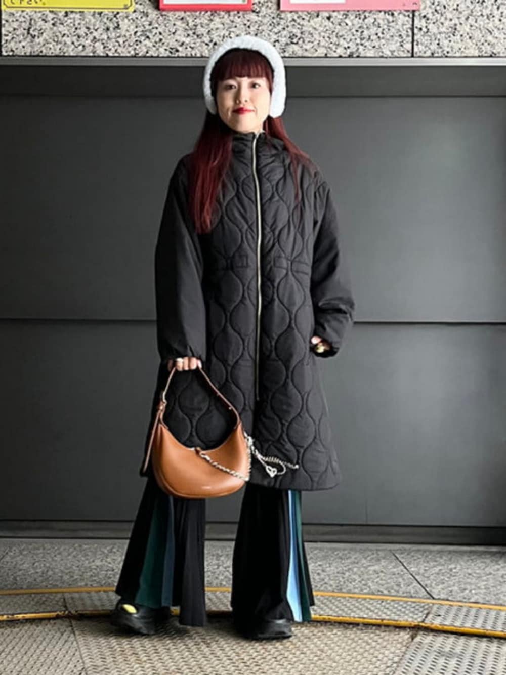 ブラウン系のトートバッグ、ブラック系のその他アウター、グレー系のイヤーマフを着用したレディースの冬コーディネートの1枚目の写真