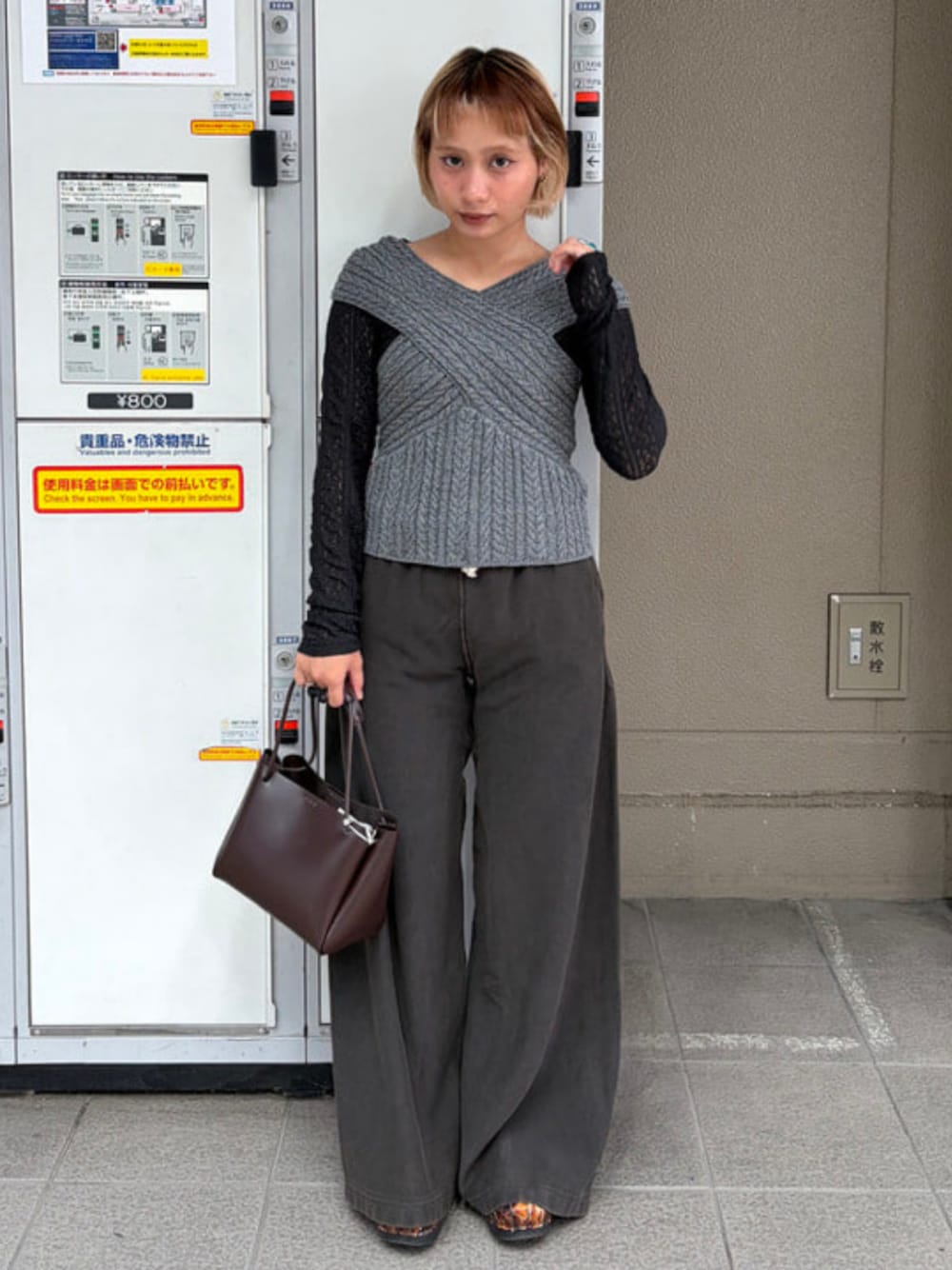 グレー系のニット/セーター、ブラック系のスウェットパンツ、ブラウン系のトートバッグを着用したレディースの夏コーディネートの1枚目の写真
