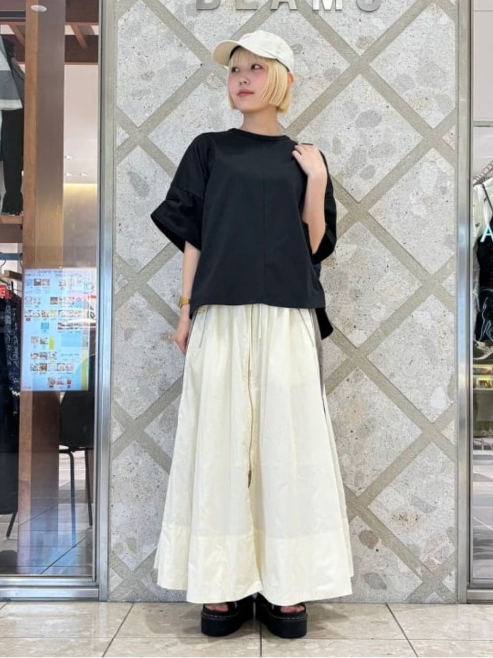 ホワイト系のスカート、ブラック系のTシャツ/カットソー、ホワイト系のキャップを着用したレディースの夏コーディネートの1枚目の写真