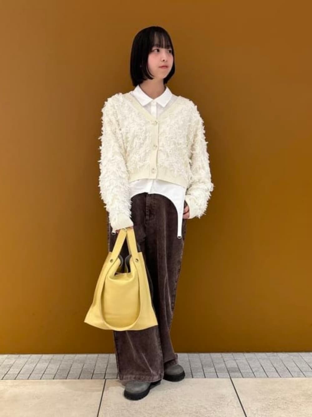 ベージュ系のトートバッグ、ブラウン系のその他パンツ、ホワイト系のカーディガン/ボレロを着用したレディースの冬コーディネートの1枚目の写真