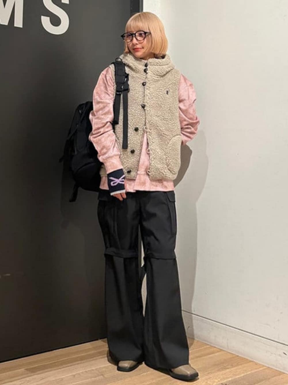 ブラック系のバックパック/リュック、ベージュ系のベスト、ピンク系のスウェットを着用したレディースの秋コーディネートの1枚目の写真