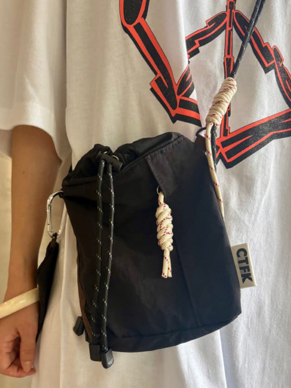 ブラック系のショルダーバッグ、ホワイト系のTシャツ/カットソーを着用したレディースの夏コーディネートの1枚目の写真