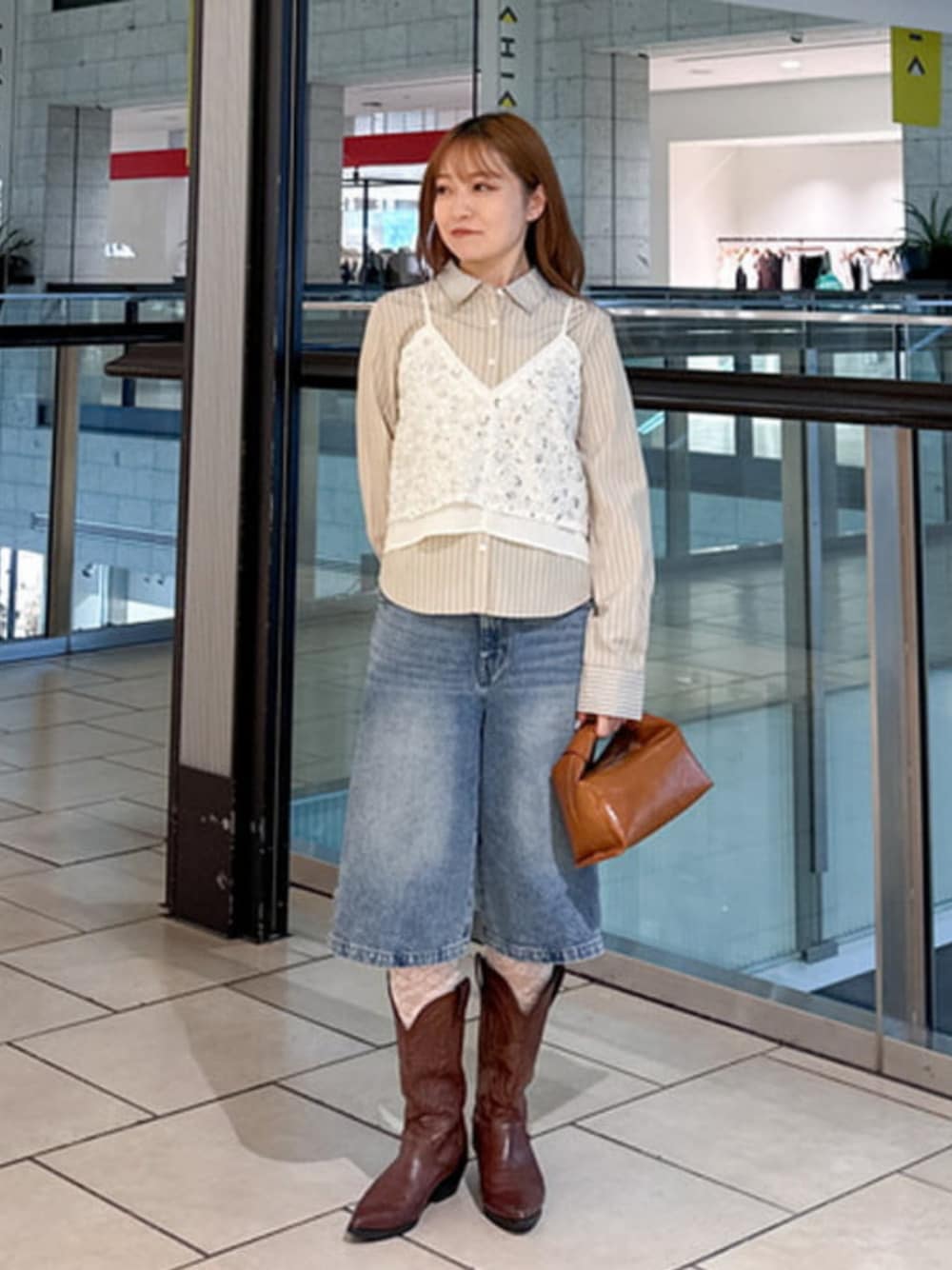 ブルー系のデニムパンツ、ブラウン系のショルダーバッグ、ホワイト系のキャミソールを着用したレディースの夏コーディネートの1枚目の写真