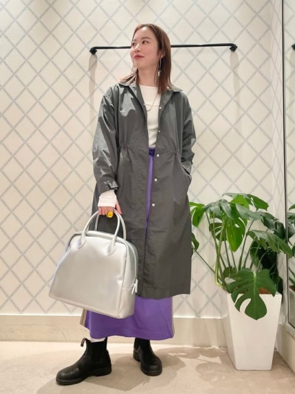 パープル系のスカート、シルバー系のボストンバッグ、グリーン系のその他アウターを着用したレディースの冬コーディネートの1枚目の写真