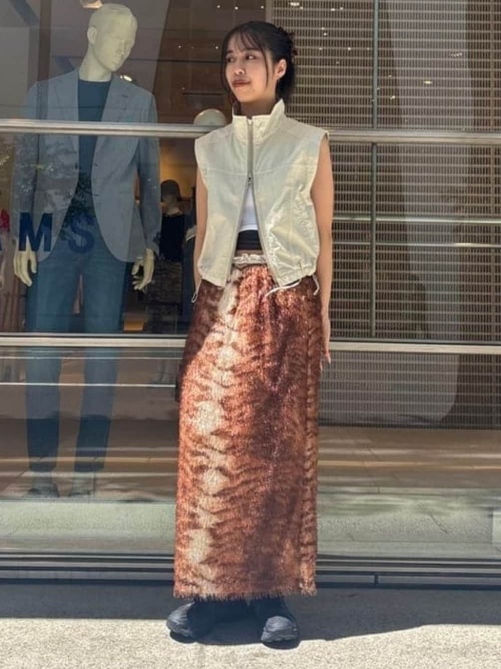 ブラウン系のスカート、ベージュ系のベストを着用したレディースの夏コーディネートの1枚目の写真