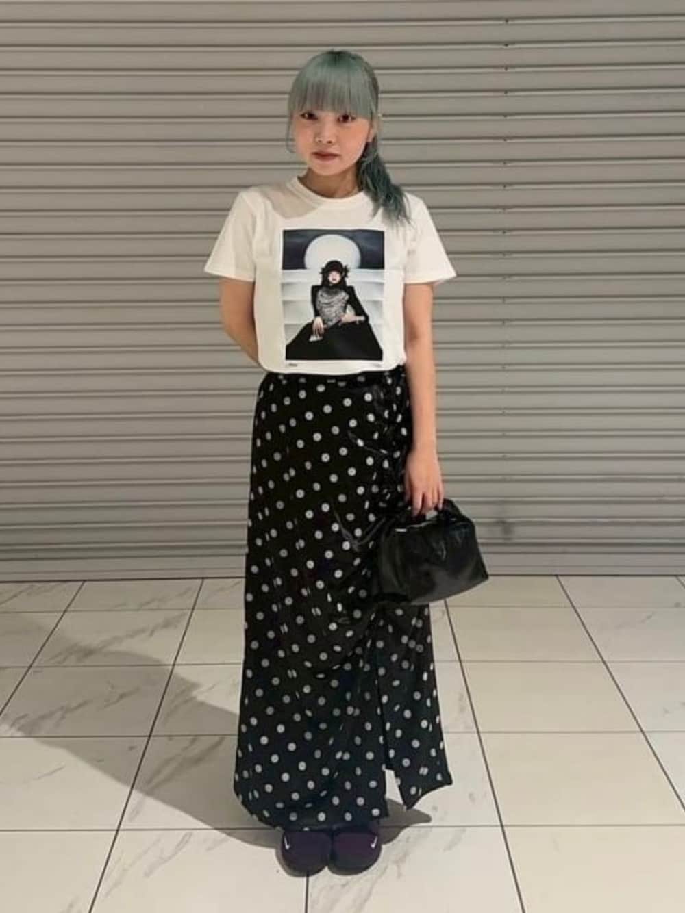 ブラック系のショルダーバッグ、ブラック系のスカート、ホワイト系のTシャツ/カットソーを着用したレディースの夏コーディネートの1枚目の写真