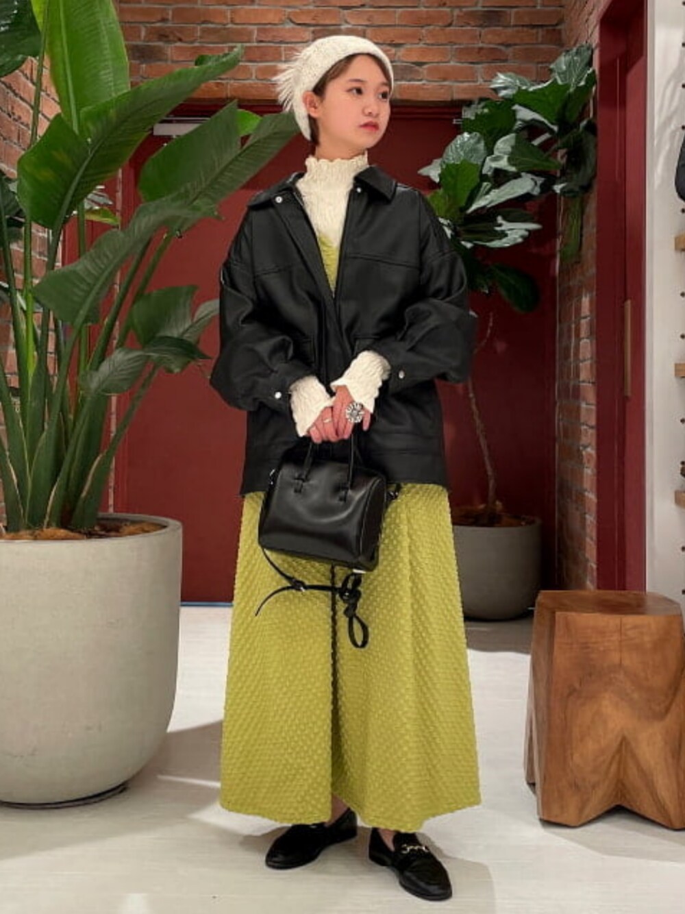 ブラック系のショルダーバッグ、ブラック系のブルゾン、グリーン系のワンピースを着用したレディースの冬コーディネートの1枚目の写真