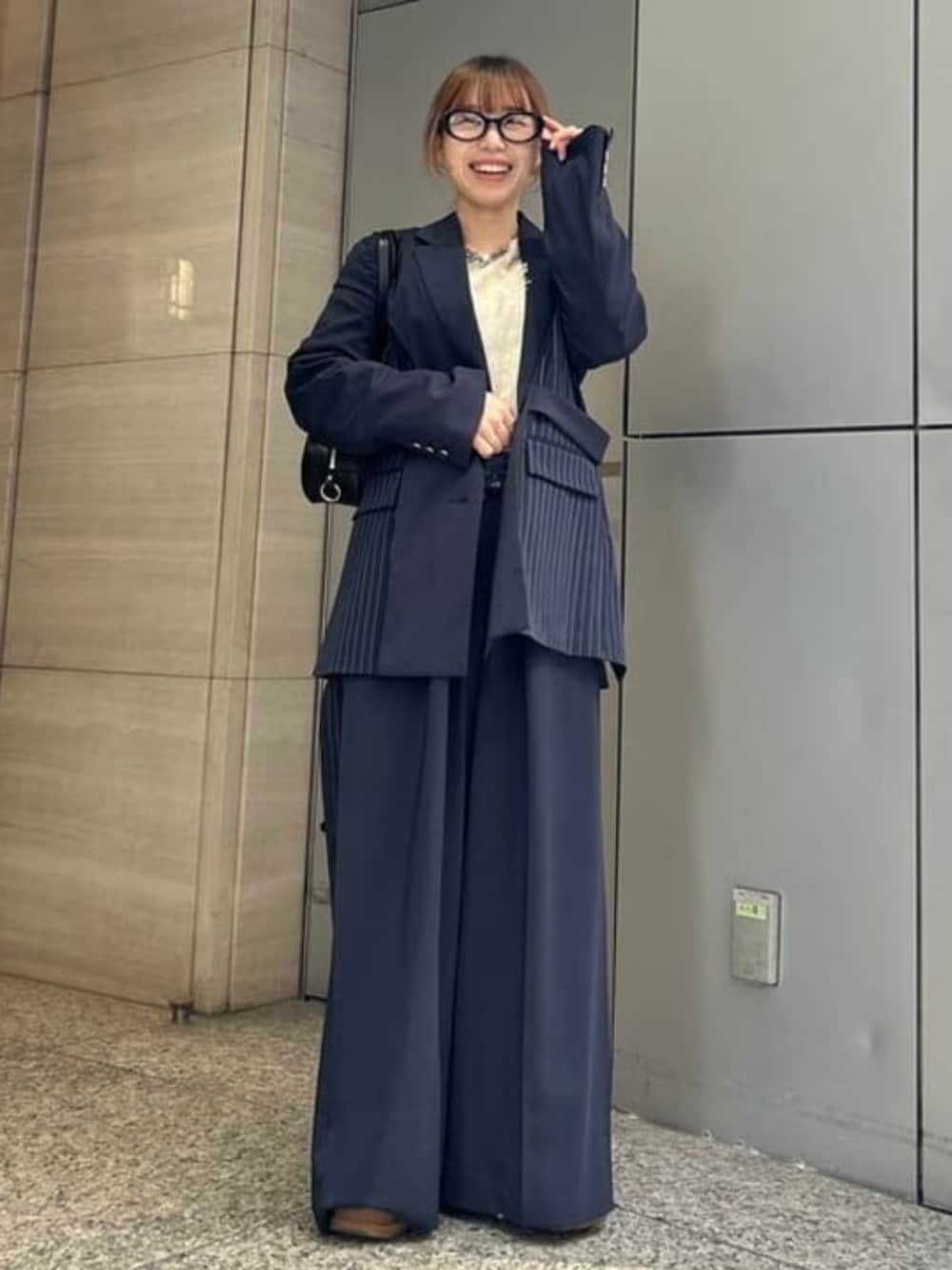 ブラック系のトートバッグ、ベージュ系のニット/セーター、ブルー系のテーラードジャケットを着用したレディースの春コーディネートの1枚目の写真