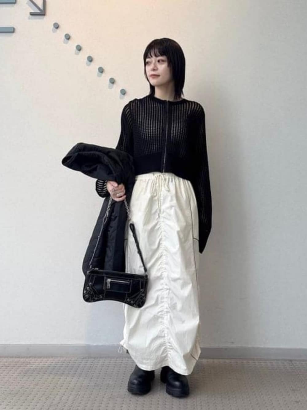 ブラック系のブルゾン、ブラック系のショルダーバッグ、ホワイト系のスカートを着用したレディースの春コーディネートの1枚目の写真