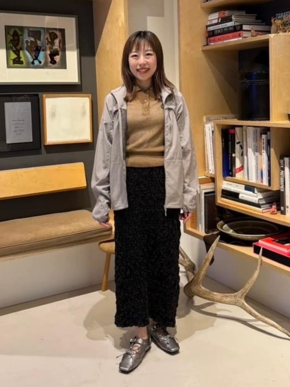 グレー系のナイロンジャケット、ブラウン系のポロシャツ、ブラック系のパンプスを着用したレディースの春コーディネートの1枚目の写真