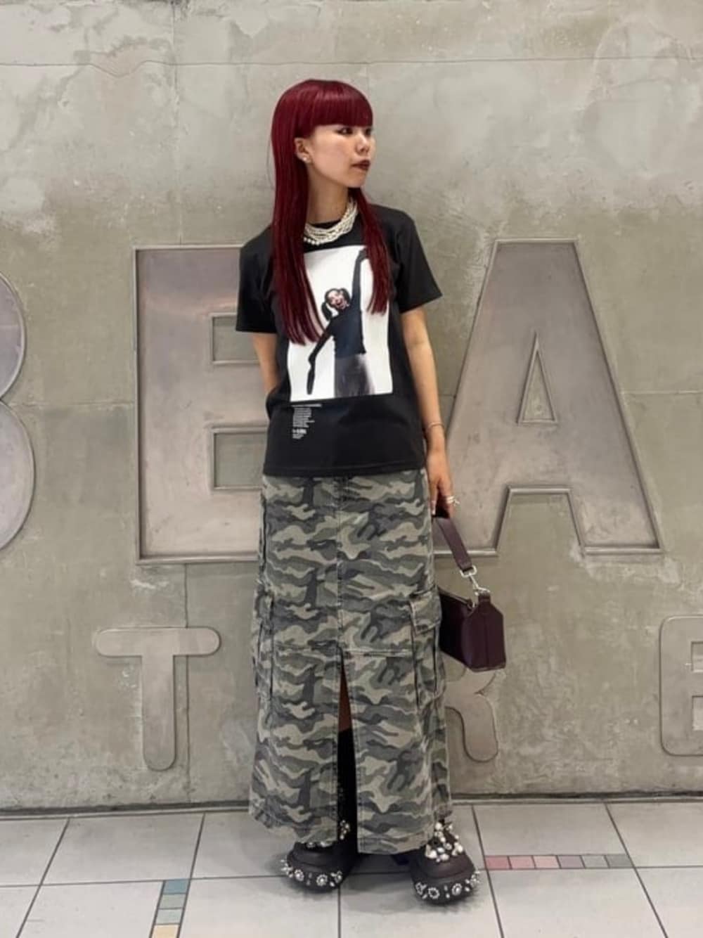 ブラウン系のトートバッグ、ブラック系のTシャツ/カットソー、グリーン系のスカートを着用したレディースの夏コーディネートの1枚目の写真