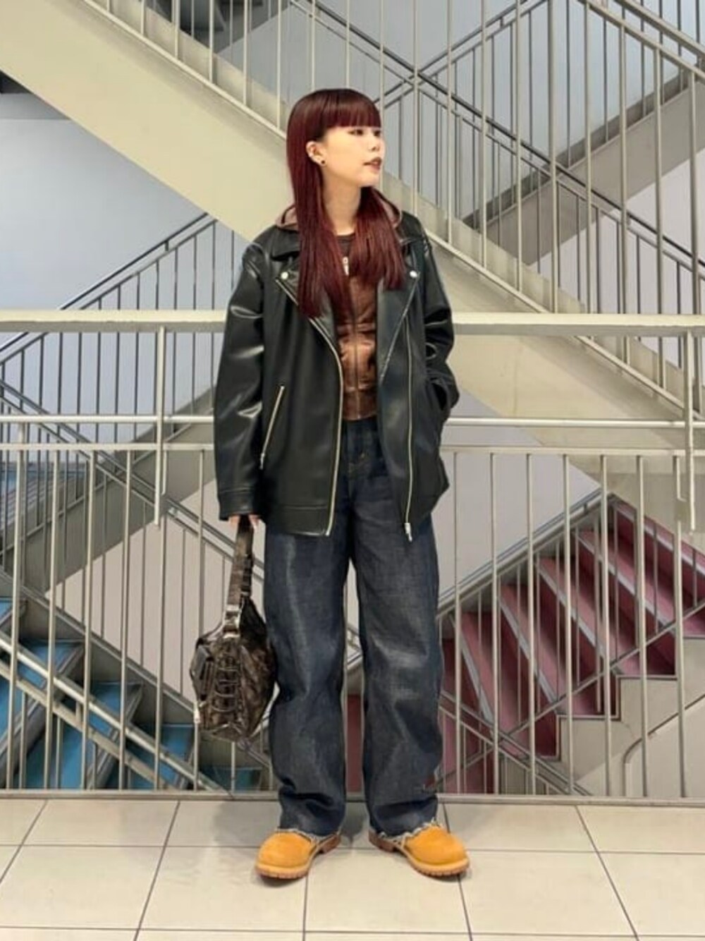 ブラウン系のトートバッグ、ブラック系のライダースジャケットを着用したレディースの冬コーディネートの1枚目の写真